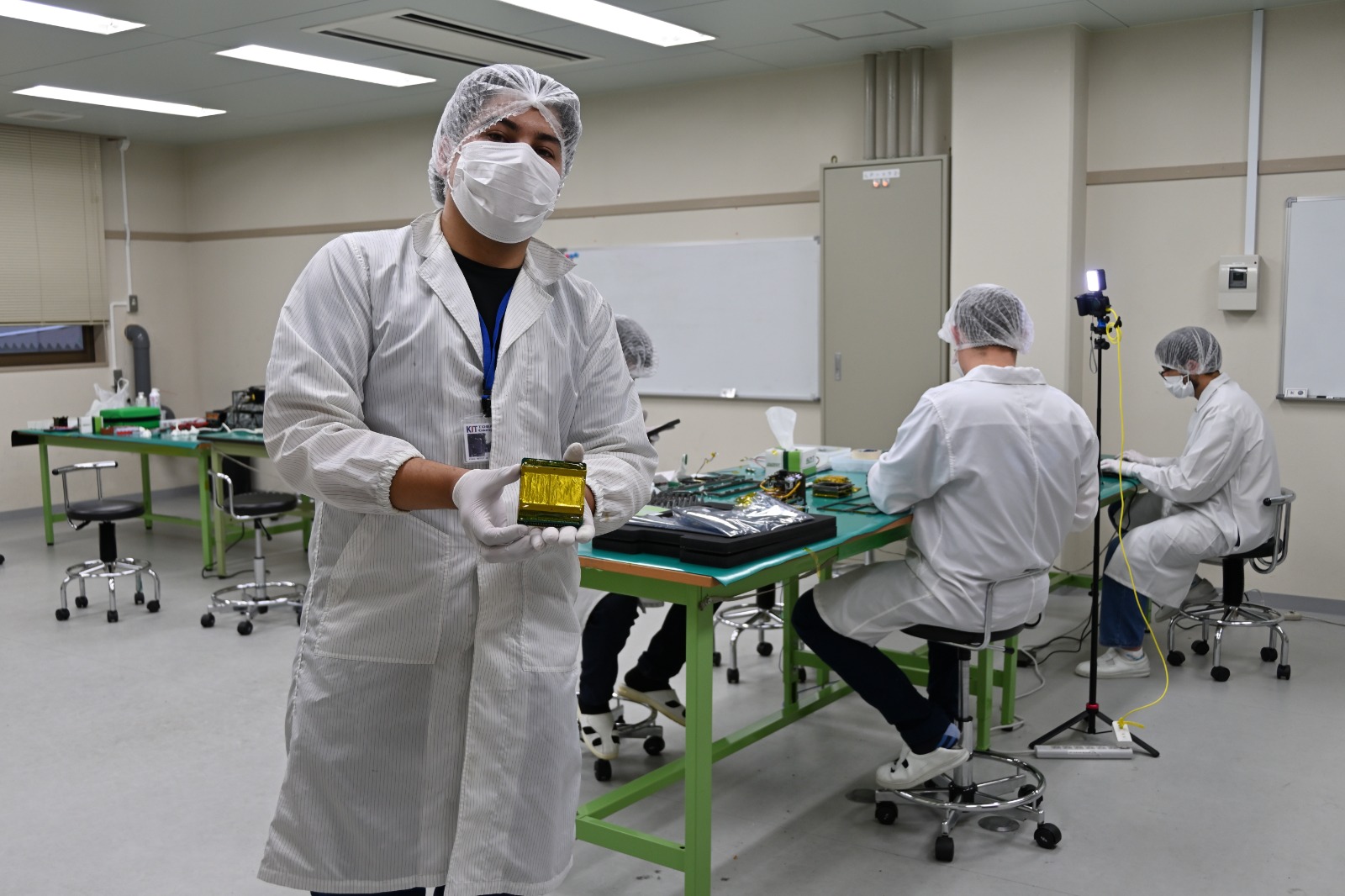 Integrante del equipo sosteniendo MUA dentro de la sala limpia de Kyutech.