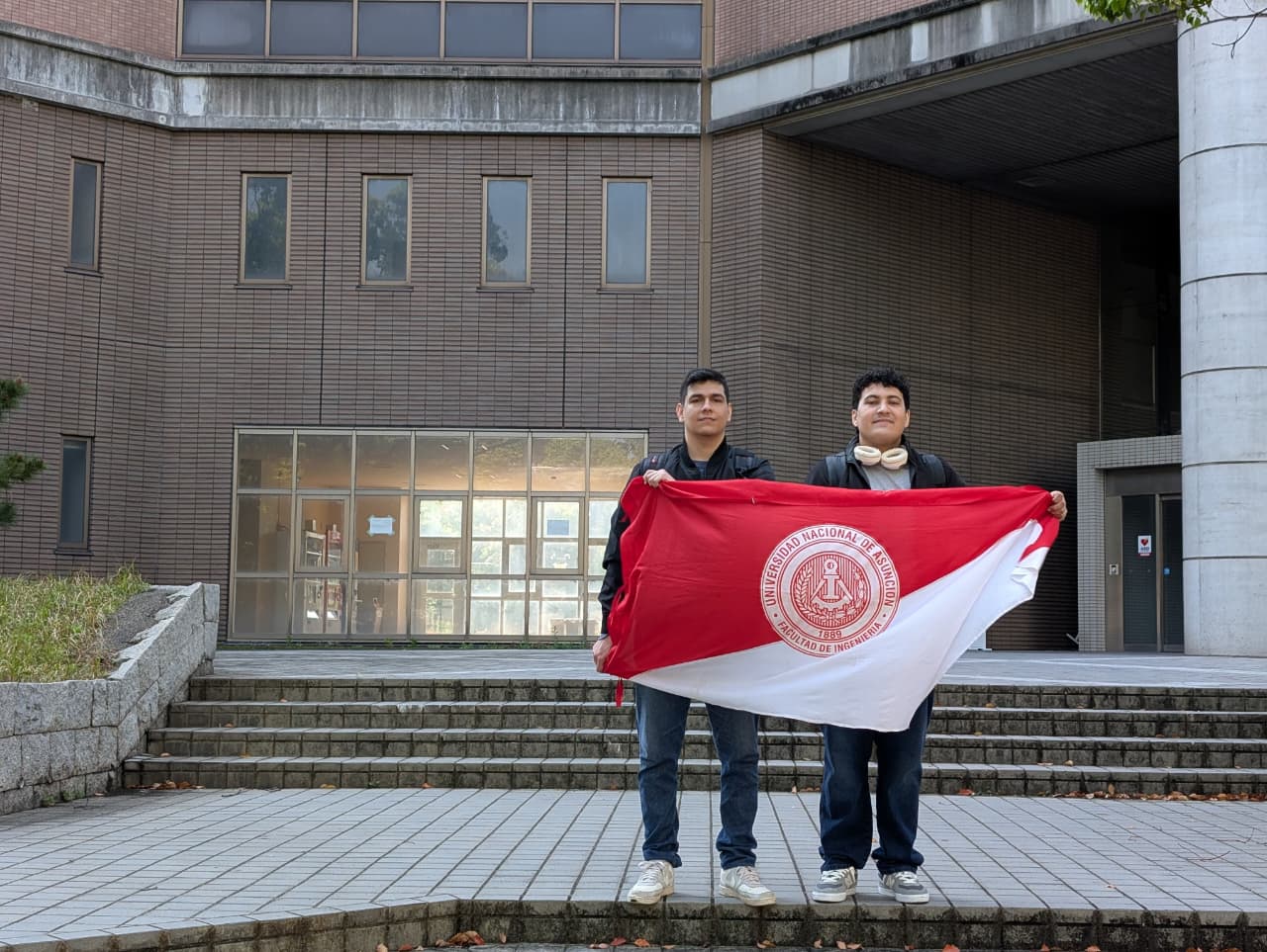 Matías Candia y Derlis Sanabria con la bandera de FIUNA durante el segundo viaje a Japón.